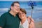 Modern sweet and loving hispanic mature couple taking selfie portrait- senior retired husband and wife on their 70s enjoying beach