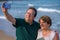 Modern sweet and loving hispanic mature couple taking selfie portrait- senior retired husband and wife on their 70s enjoying beach