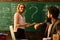 Modern teacher hipster writing on big blackboard with math formula, Teacher respects students, Smiling adult students