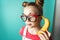 Modern technology: A teenager girl in funny glasses uses a yellow banana as a phone.