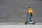 Modern teenager with backpack rides on electric scooter on brick wall background. Boy comes back from school