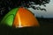 Modern tent lit from inside in wilderness at night