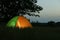 Modern tent lit from inside in wilderness at night. Overnight camping