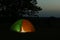 Modern tent lit from inside in wilderness at , space for text. Overnight camping