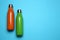 Modern thermo bottles on light blue background, flat lay. Space for text