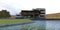 A modern three-story cozy house on the shore of an artificial lake. Straight lines, flat roof, spacious terraces. 3d render