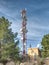 Modern tower with huge complex of telecommunication antennas on old bricks house hidden in pine trees.  Mountain trail over Pintal