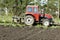 Modern tractor machinery plowing agricultural field meadow at farm at spring autumn. Farmer cultivating and make soil