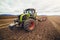 Modern tractor working on the farm, a modern agricultural transport, cultivation of fertile land, tractor on cloudy sky background