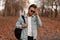 Modern trendy young man with a stylish hairstyle in black sunglasses in a denim jacket with a backpack posing in the autumn forest