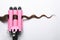 Modern triple curling iron with brown hair lock on white background, top view