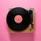 Modern turntable with vinyl record on pink background, top view