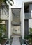 Modern urban office building entrance door with tropical outdoor garden, pond and cement path