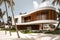 Modern villa on a tropical sand beach among palm trees. Minimalist house with round curved shaped forms. Created with generative