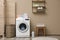 Modern washing machine near color wall in laundry room interior