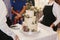 Modern wedding cake at wedding reception. Waiters taking out stylish white wedding cake with floral decor and mr mrs topper at