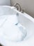 Modern White Bathtub Filled with Running Water from a Brushed Nickel Faucet