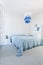 Modern white and blue chandelier in trendy spacious bedroom with king size bed