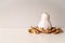 Modern white colored pumpkin with golden stem on the pile of dry autumn leaves on white table with copy space