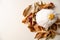 Modern white colored pumpkin with golden stem on the pile of dry autumn leaves on white table top view flat lay