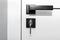 Modern white door with matte black handle and magnetic locks, lock with key inserted.
