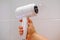 Modern white hair dryer for drying and styling hair in female hand, woman in bathroom dries hair after washing, hair care concept