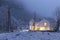 Modern white house with light windows surronded by mountain, snow and trees. Chirstmas mood