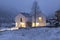 Modern white house with light windows surronded by mountain, snow and trees. Chirstmas mood