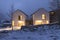 Modern white house with light windows surronded by mountain, snow and trees. Chirstmas mood