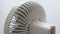 Modern white portable electric fan on light white background. The curtain develops in the wind by the window. Back view