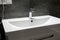 Modern white rectangular sink with chromed metal faucet for hot and cold water in a stylish bathroom with gray concrete wall