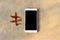 Modern white smartphone, cell phone with blank black display on table. Golden marble background with dry oak leaf