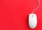 Modern wired optical mouse on red background. Space for text