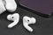 Modern wireless earbuds headphones with charging case iand smartphone on stone table background. Earphones for smartphone and