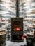 Modern wood burning stove. Tiled wall behind, stove with fire burning inside, cosy and warm interior scene, heating in winter