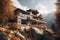 A modern wood and stone house on a rocky hillside, surrounded by autumn trees, with a balcony facing the snow-covered mountains, a