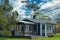 Modern wooden house with green grass, trees and sky with clouds at the background