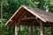 Modern wooden roof, canopy, on a background of green trees.