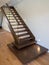 Modern wooden staircase with glass balustrade and mirror on back wall