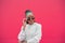 Modern young girl blogger straighten stylish sunglasses looking aside on copy space for advertising on pink background