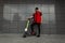 Modern young hipster man in stylish red-black jeans clothes in sports sneakers in sunglasses with a vintage scooter stands