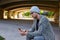 Modern young man with smartphone under bridge