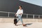 Modern young man in stylish clothes in sunglasses in red leather sandals with a vintage black bag travels on a bright sunny day