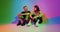 Modern young teen romantic couple sitting and talking having fun together in colourful neon studio light