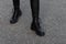 Modern young woman in black stylish leggings in fashionable leather boots stands on the road in the city. Trendy collection of