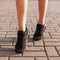 Modern young woman with slender beautiful legs in fashionable black sneakers walks down the street. Stylish sporty women`s shoes.