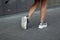Modern young woman with slender beautiful legs in fashionable silver sneakers walks on the street. Stylish women`s shoes. Summer