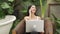 Modern young woman working remotely or relaxing in tropical garden. Blithe