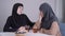 Modest Muslim woman in hijab calming down her modern-looking female friend. Young lady comforting and hugging crying