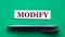 MODIFY - word on a green background with a black handle